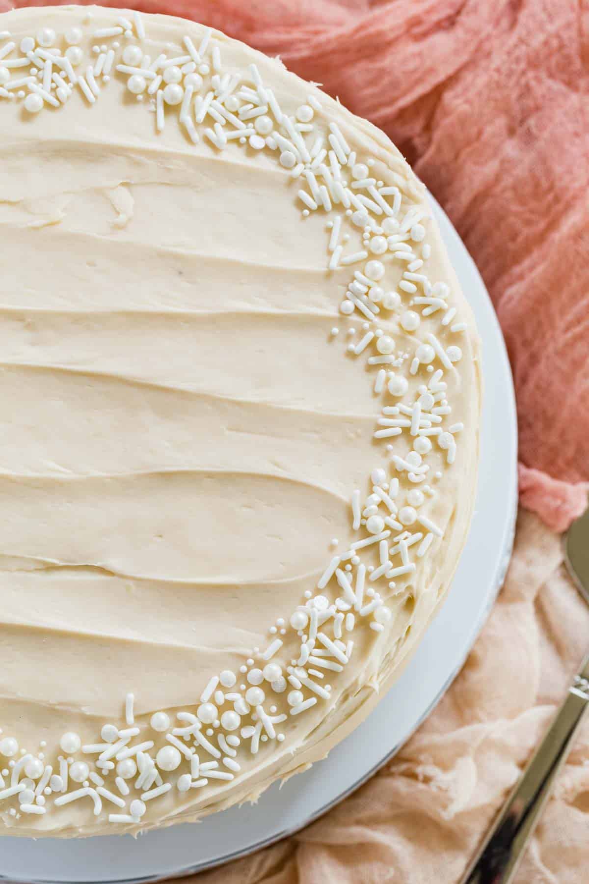 Top view of a full gluten free hummingbird cake on a plate, garnished with sprinkles.