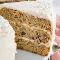 A slice of gluten free hummingbird cake is lifted from the rest of the cake.