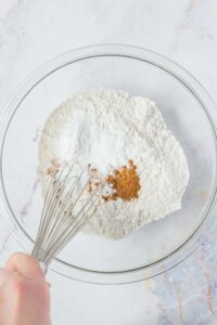 The dry ingredients for hummingbird cake are whisked together in a mixing bowl.