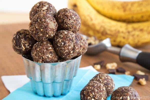 Chunky Monkey Energy Balls in a silver cup with bananas, walnuts, and chocolate chunks in the background