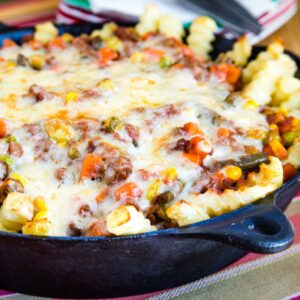 Shepherd's Pie Loaded Fries toped with melted cheese in a cast iron skillet.