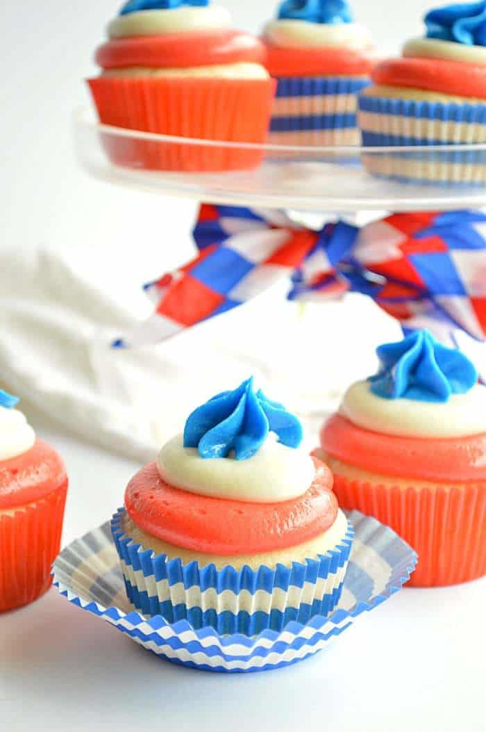4th of july cupcakes with red white and blue frosting on a table and a glass cake stand