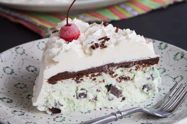 A piece of Homemade No-Churn Mint Chocolate Chip Ice Cream Cake with a cherry on top