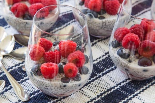 Triple Berry Coconut Chia Pudding Parfaits on a blue and white checked placemat