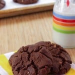 Flourless Chocolate Almond Cookies on a striped napkins with more on a cookie sheet