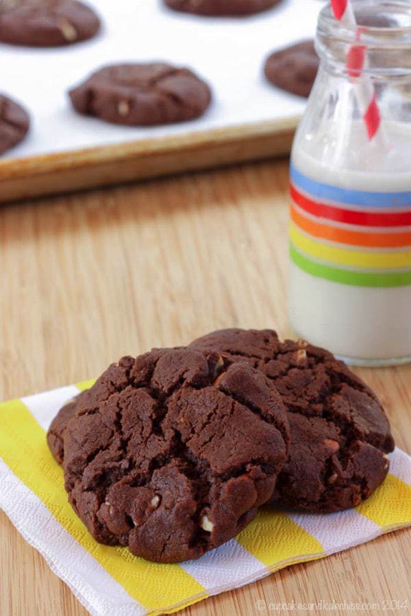 Flourless Chocolate Almond Cookies on a striped napkins with more on a cookie sheet