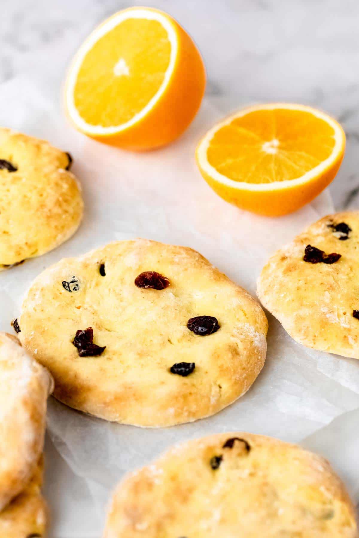 Assorted cranberry orange pita bread on a marble countertop next to two halves of an orange.