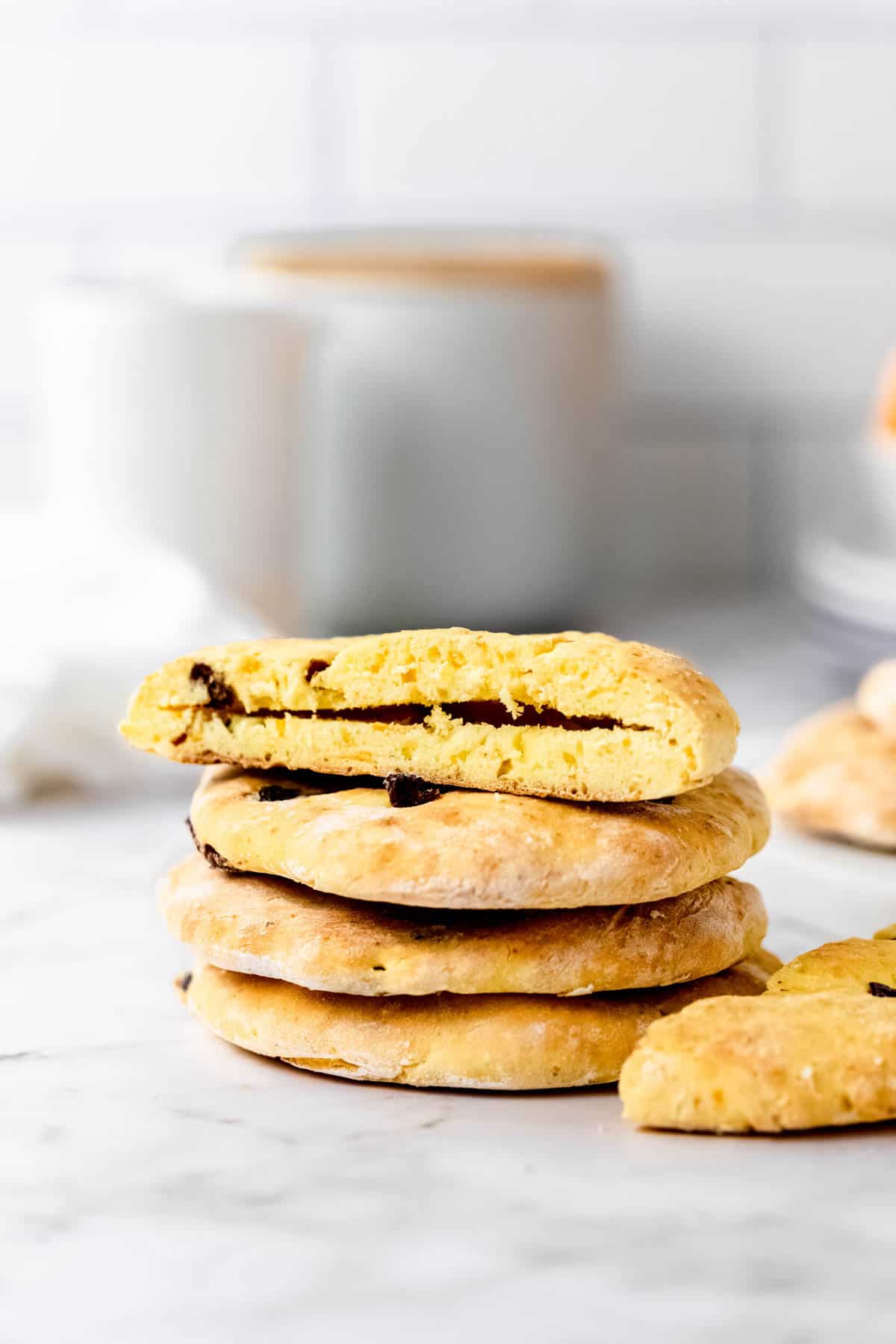 A stack of gluten-free cranberry orange pita bread on a marble countertop with the top pita sliced open.