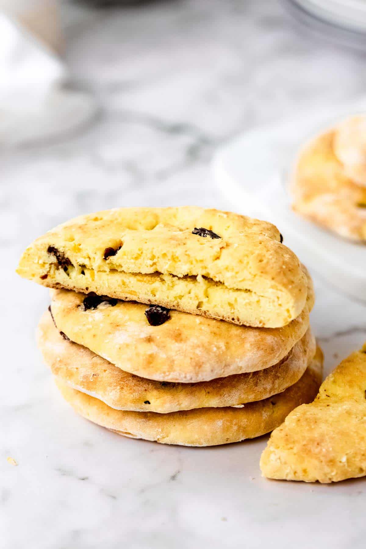 A stack of gluten-free cranberry orange pita bread on a marble countertop with the top pita sliced open.