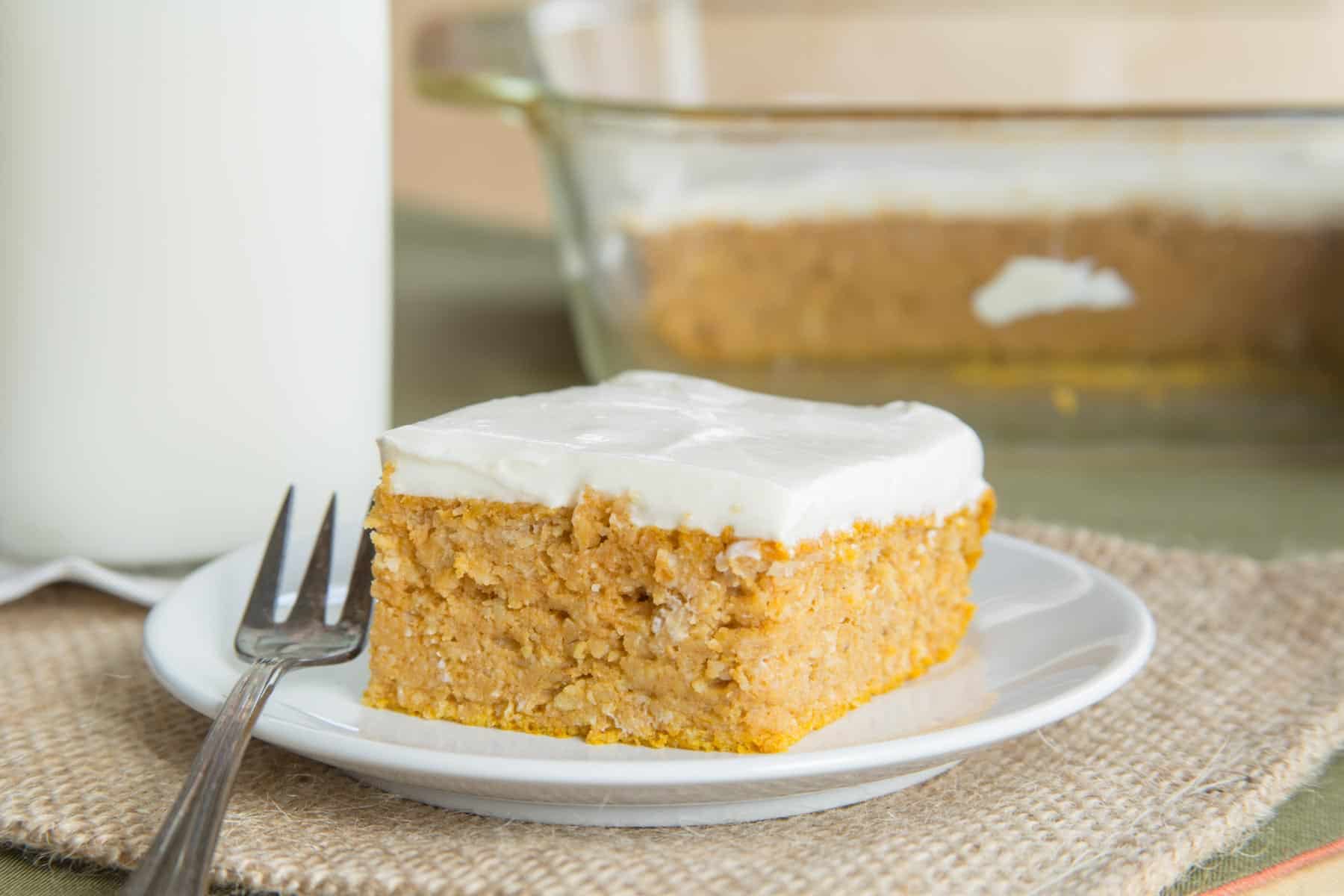 Healthy snack cake being served on a white plate in front of the rest of the cake in a glass baking pan