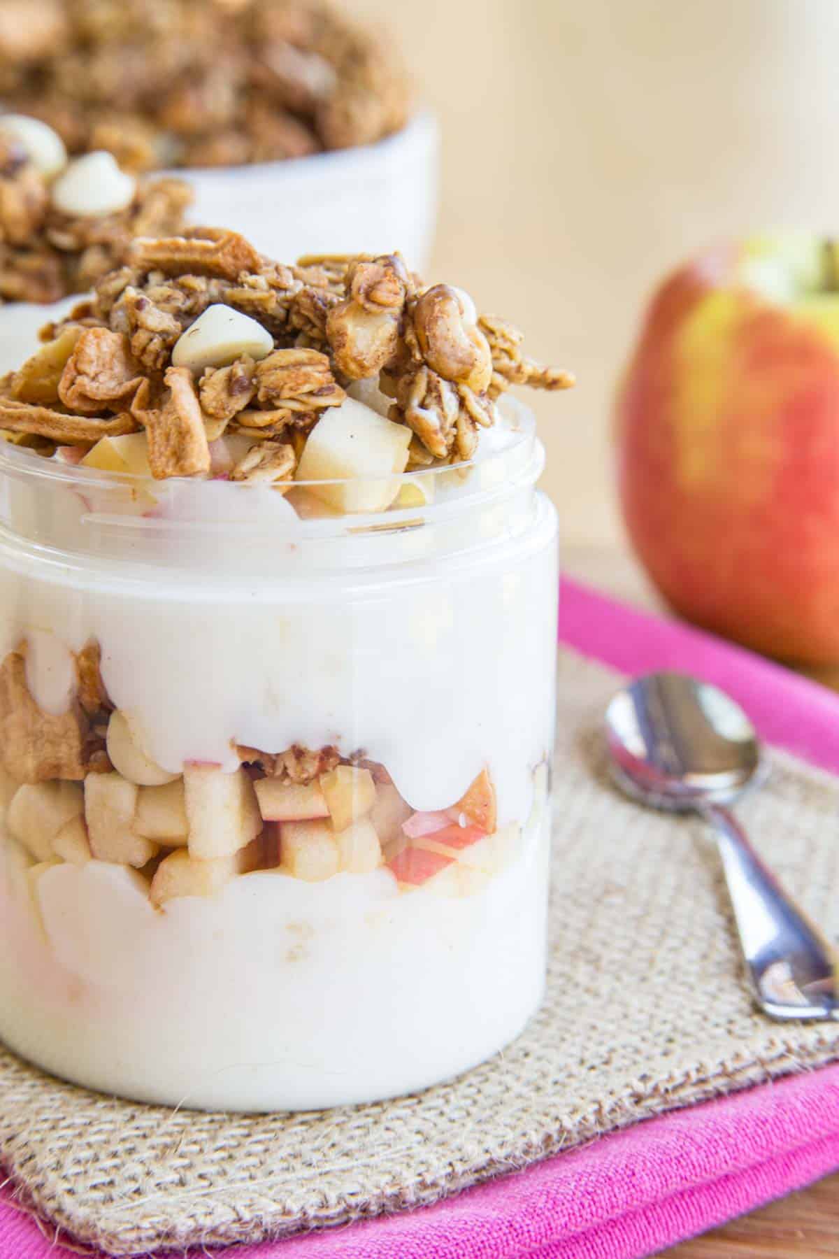 A closeup of the side of an apple parfait to show the yogurt, apple, and granola layers.