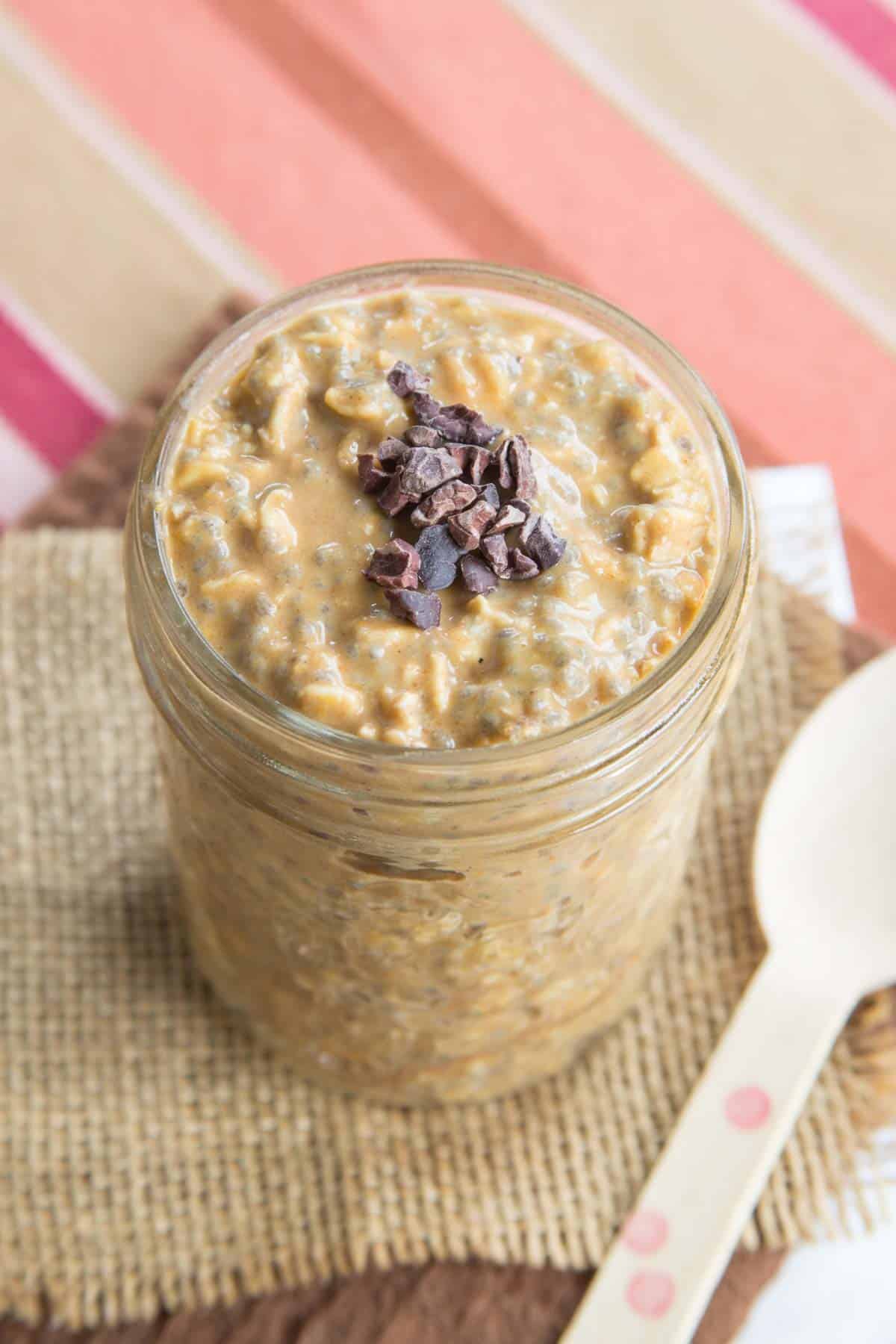 Looking down at the surface of a jar of overnight oats with cacao nibs on top.