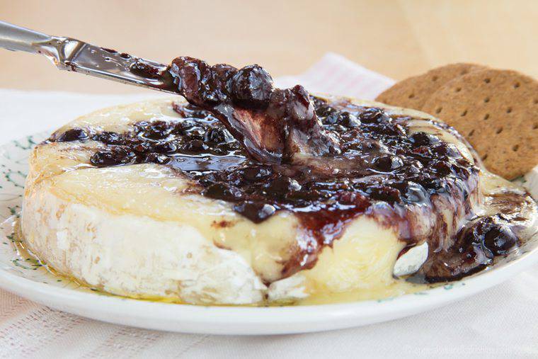 Picking up Balsamic Blueberry Baked Brie with a knife