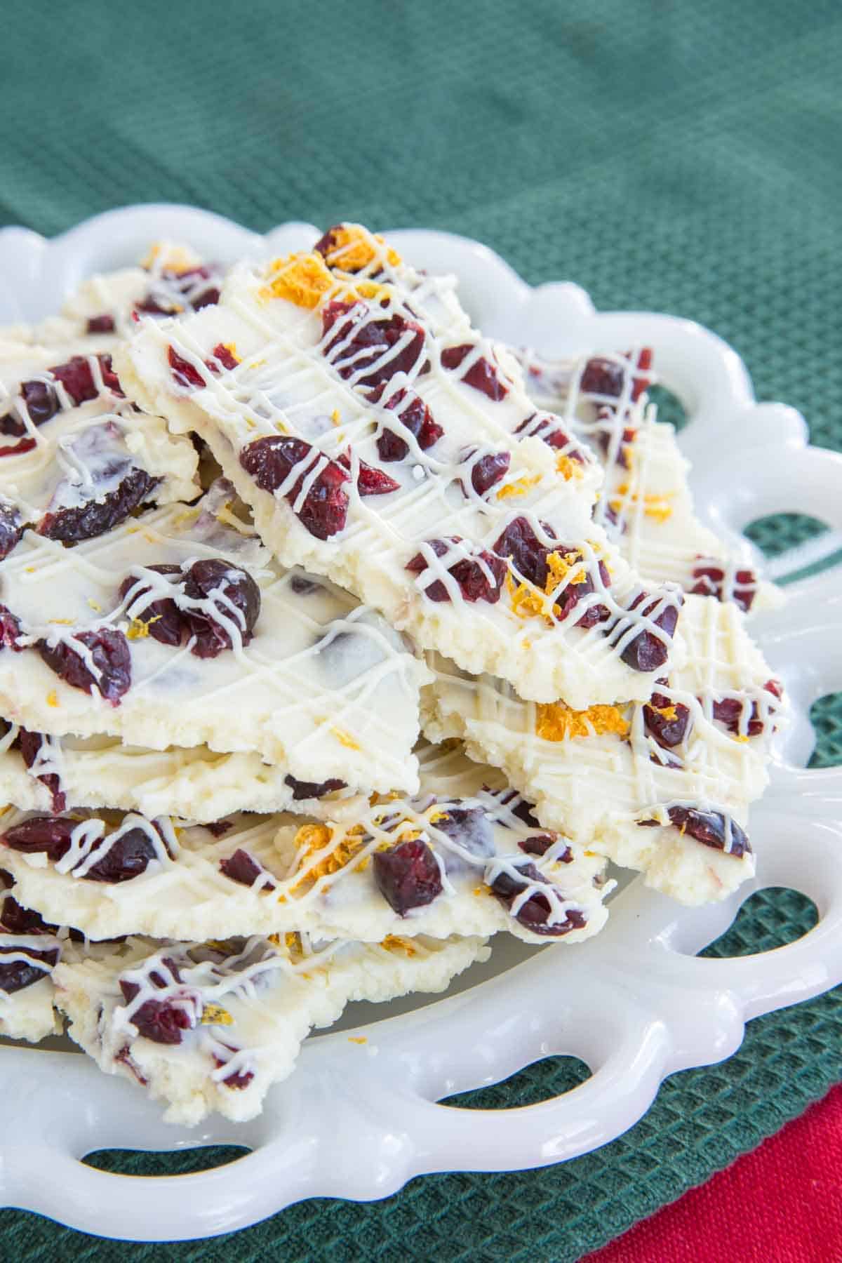 Cranberry-studded white chocolate bark on a white plate on top of a green cloth napkin.