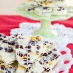 white chocolate bark with dried cranberries piled on a plate and a cake stand