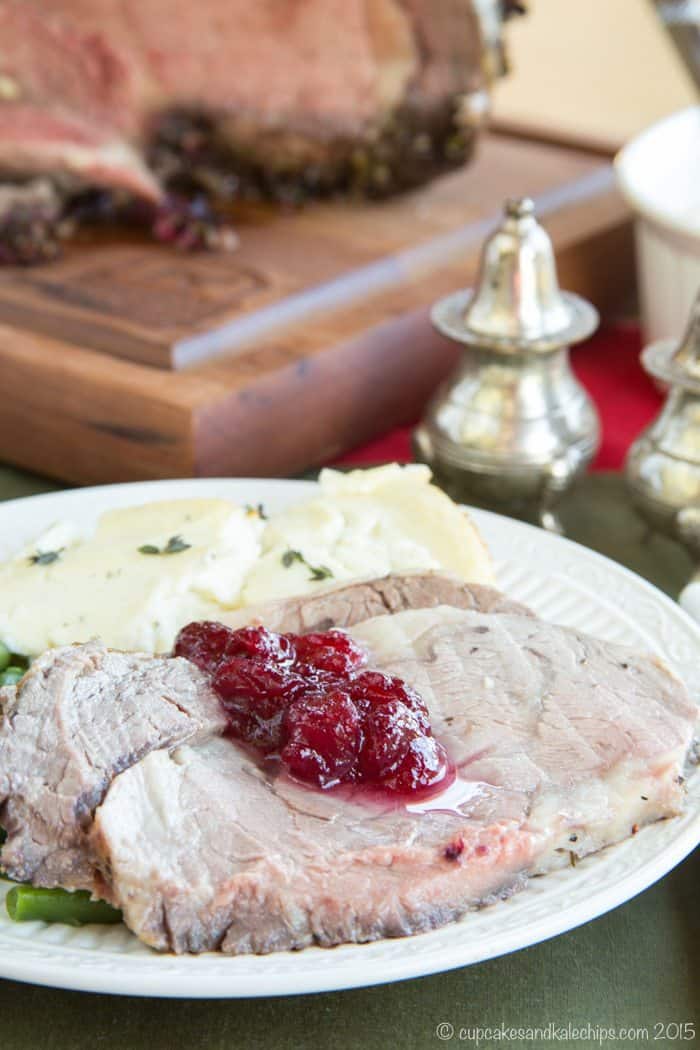 Slices of Cranberry Crusted Prime Rib Roast on a plate topped with cranberry sauce