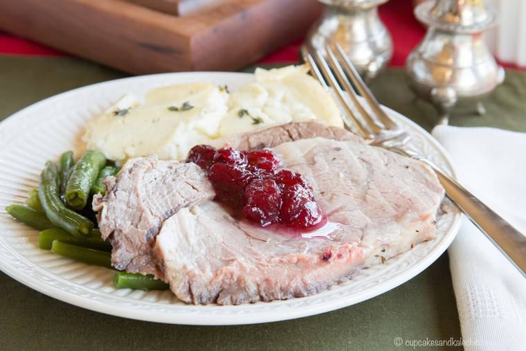 Cranberry Crusted Prime Rib topped with cranberry sauce on a plate with side dishes