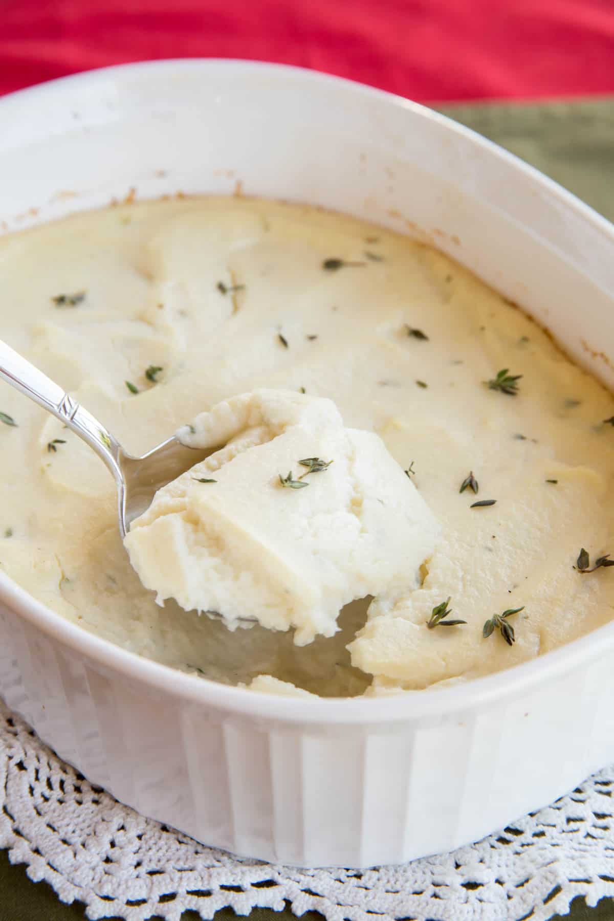 A serving spoon in a casserole dish of Whipped Cauliflower Gratin with Goat Cheese and Thyme