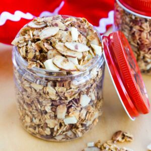 Slow Cooker Eggnog Granola in a jar with a red lid leaning against it.