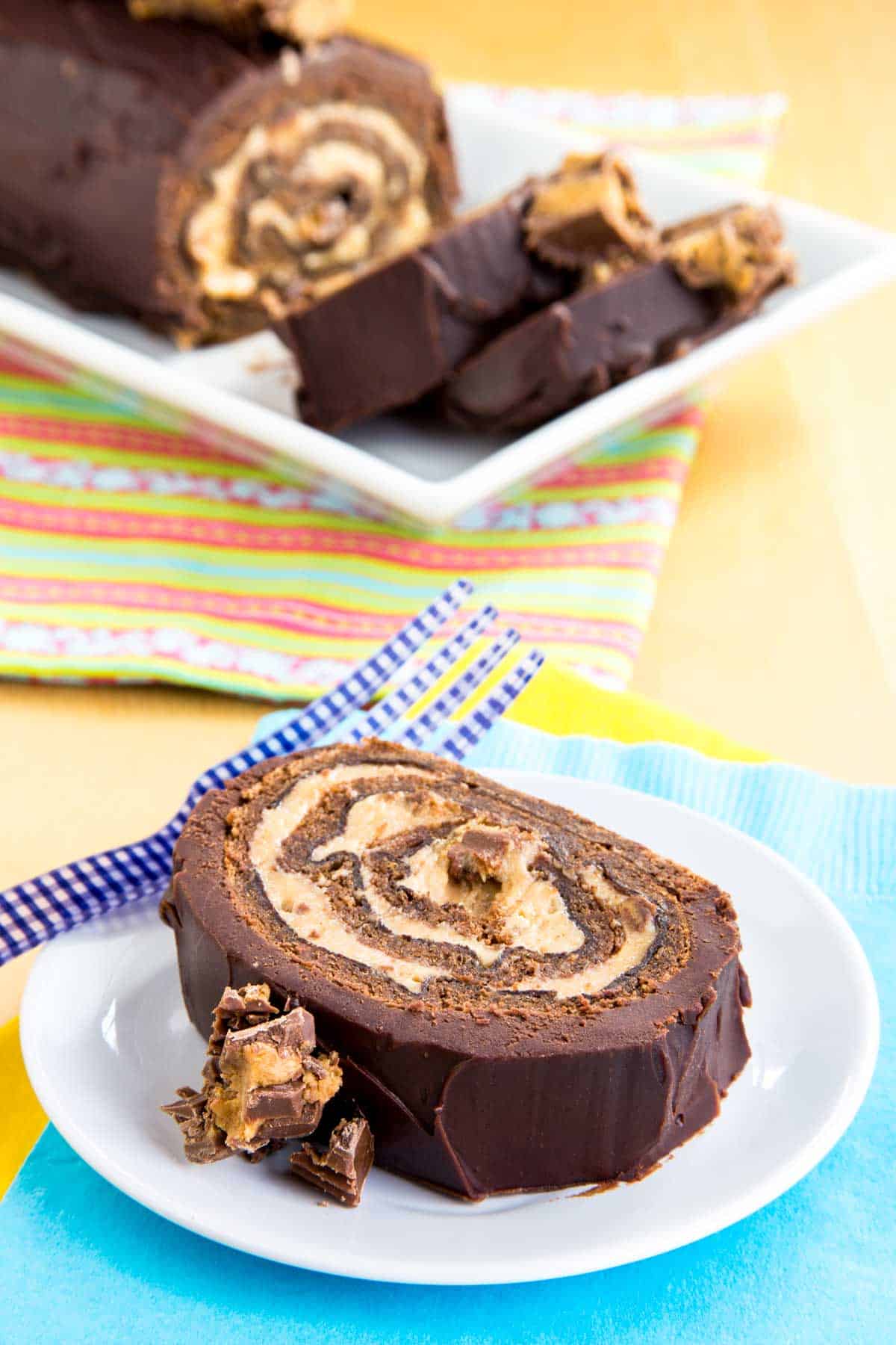 A slice of Flourless Chocolate Peanut Butter Roll Cake topped with Reese's