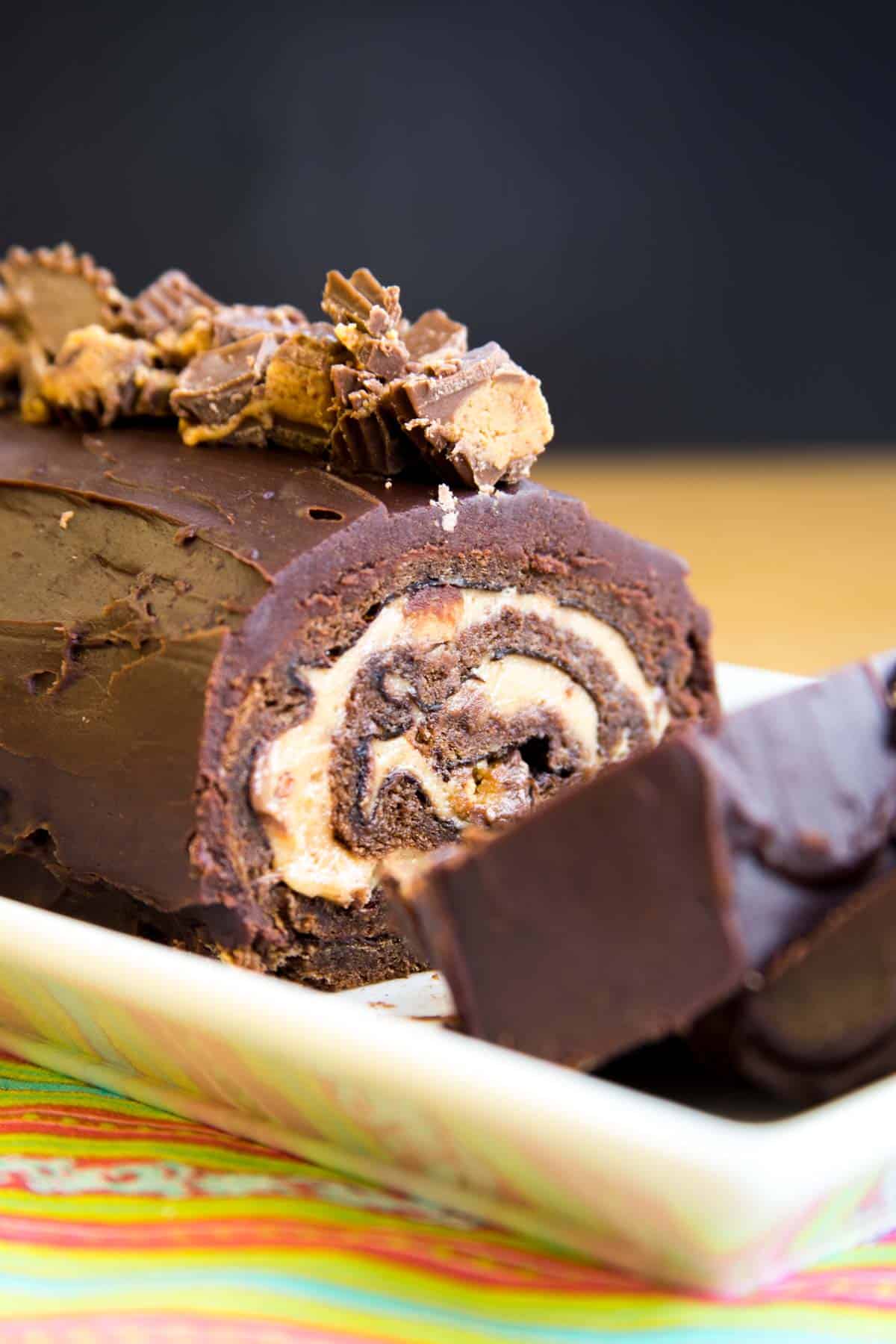 Peanut Butter Cup Flourless Chocolate Cake Roll on a serving plate with some slices lying down