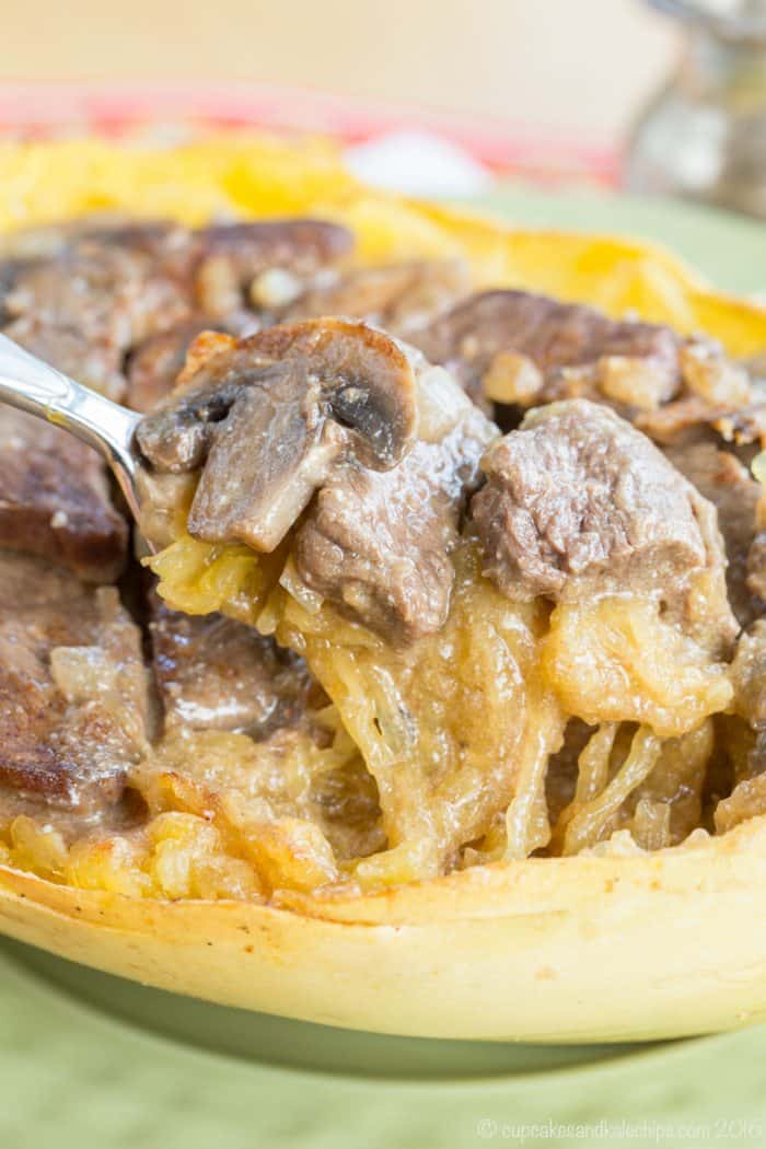 Fork picking up slices of beef and mushrooms with spaghetti squash