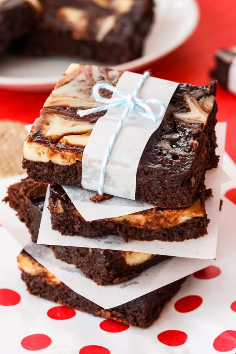 A stack of cheesecake-swirled brownies wrapped with a strip of wax paper and bakery twine.