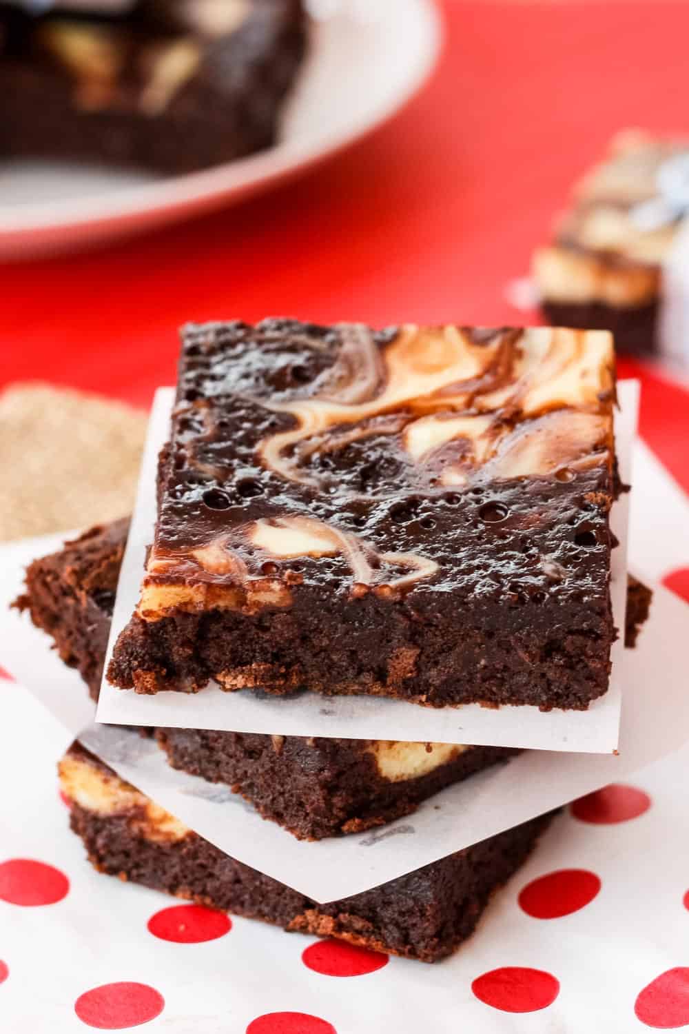 Three swirled gluten free brownies on top of each other with pieces of parchment between them.
