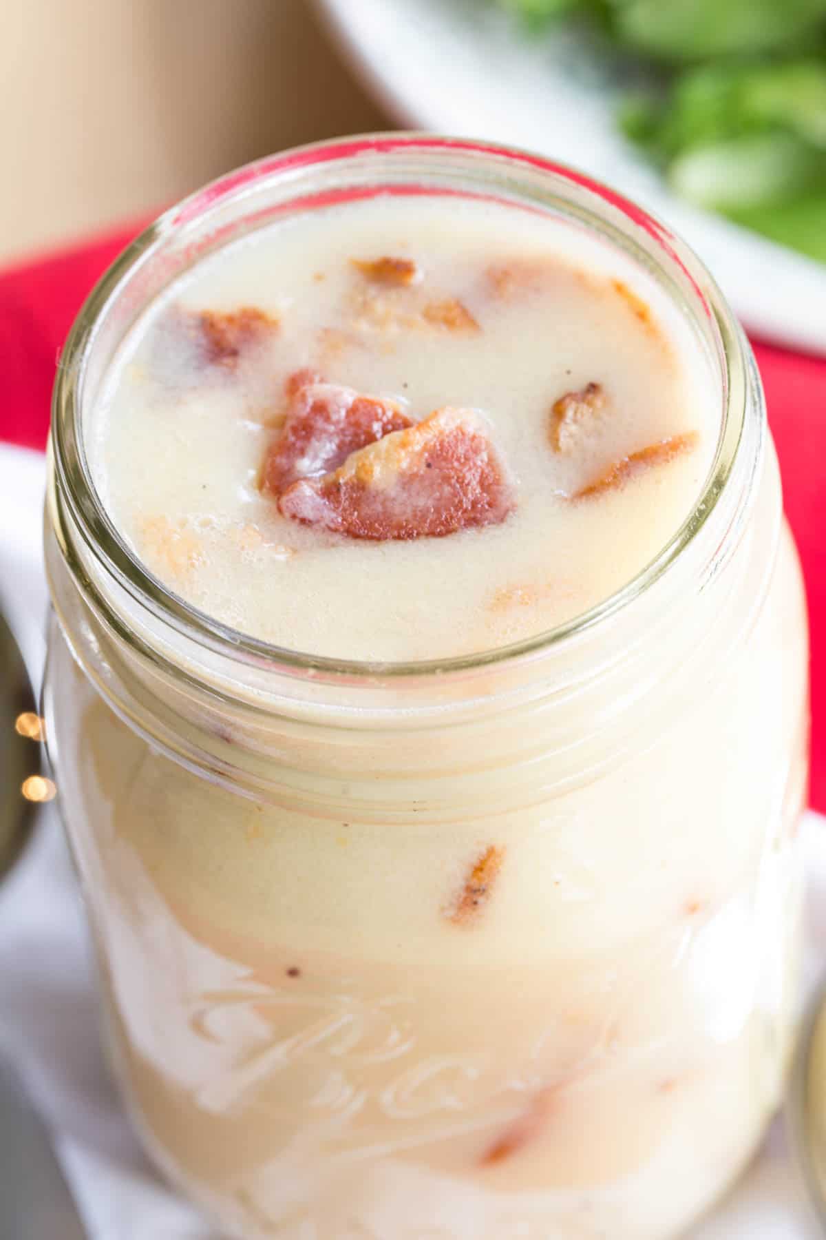 Looking down at the top of a jar of hot bacon dressing with pieces of bacon on top.