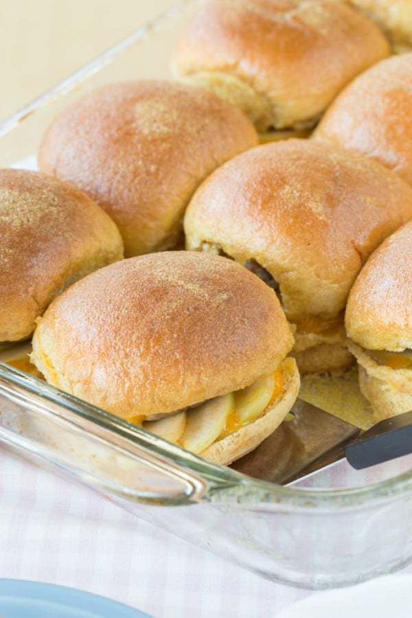 Apple turkey sausage breakfast sliders in a baking dish with a metal spatula.