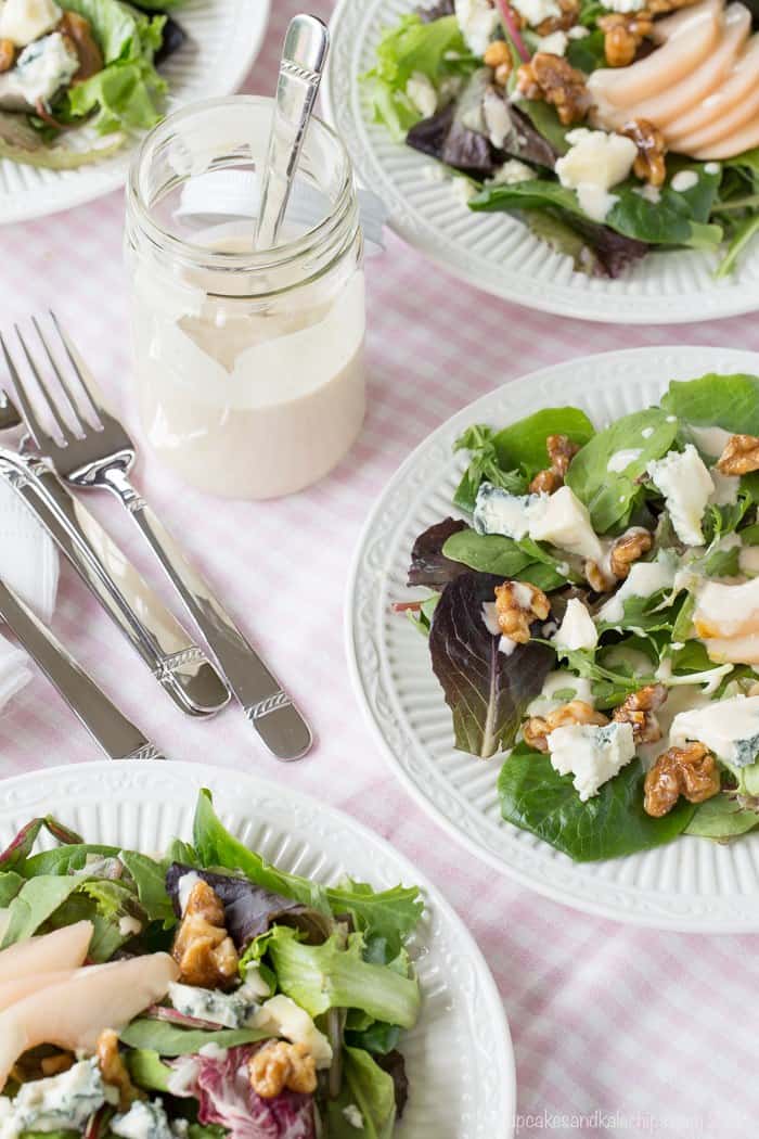 plates of mixed greens with poached pears, glazed walnuts, and blue cheese plus a jar of dressing