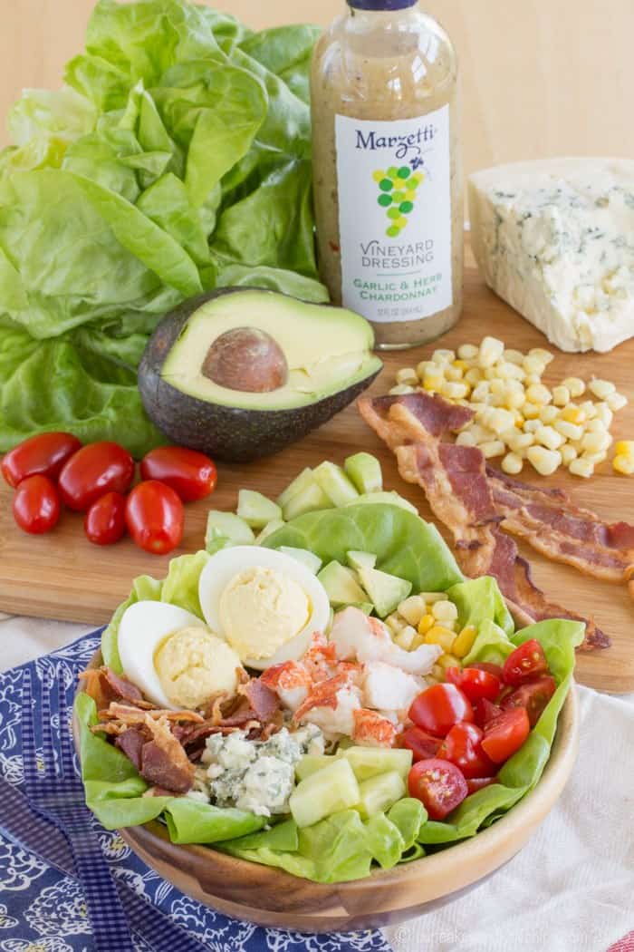 Cobb-Style Lobster Salad with bacon, avocado, corn, and tomatoes on a cutting board