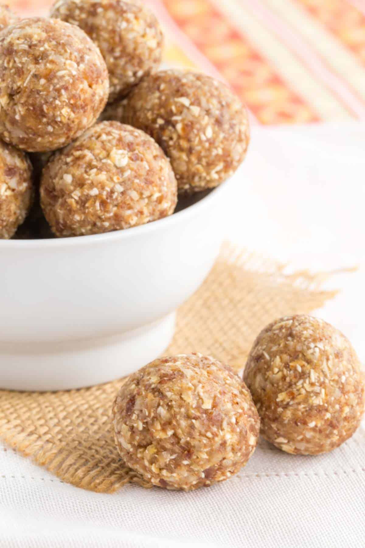 two energy bites on a napkin in front of a bowl with more inside