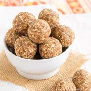 A small white bowl of pineapple coconut energy balls on a piece of burlap.
