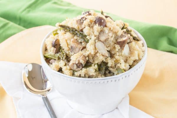White bowl of Roasted Asparagus and Mushroom Quinoa Pilaf with a serving spoon