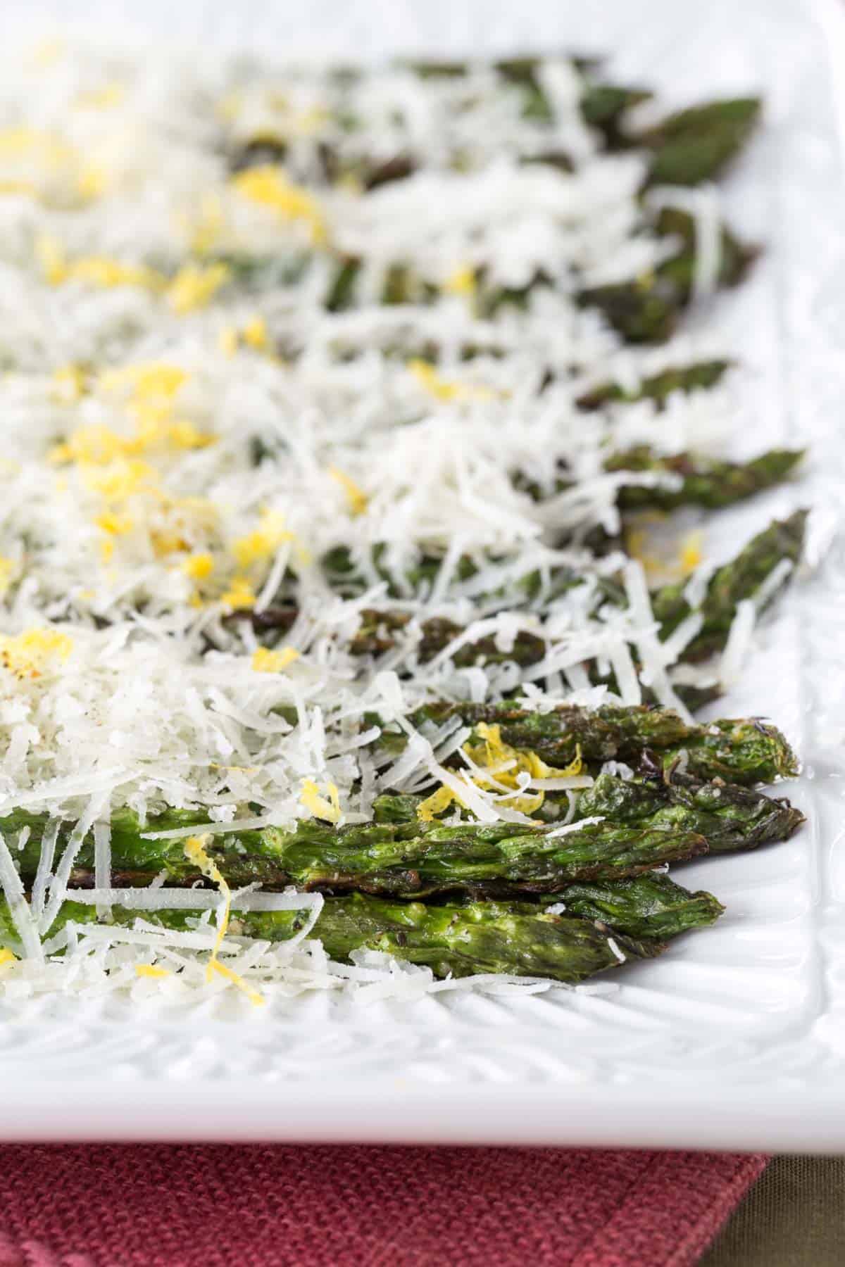 rectangular serving platter with lined up grilled asparagus with cheese and lemon zest