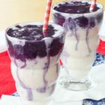 Two Honey and Vanilla Swirled Blueberry Smoothies side by side with red and white striped straws.