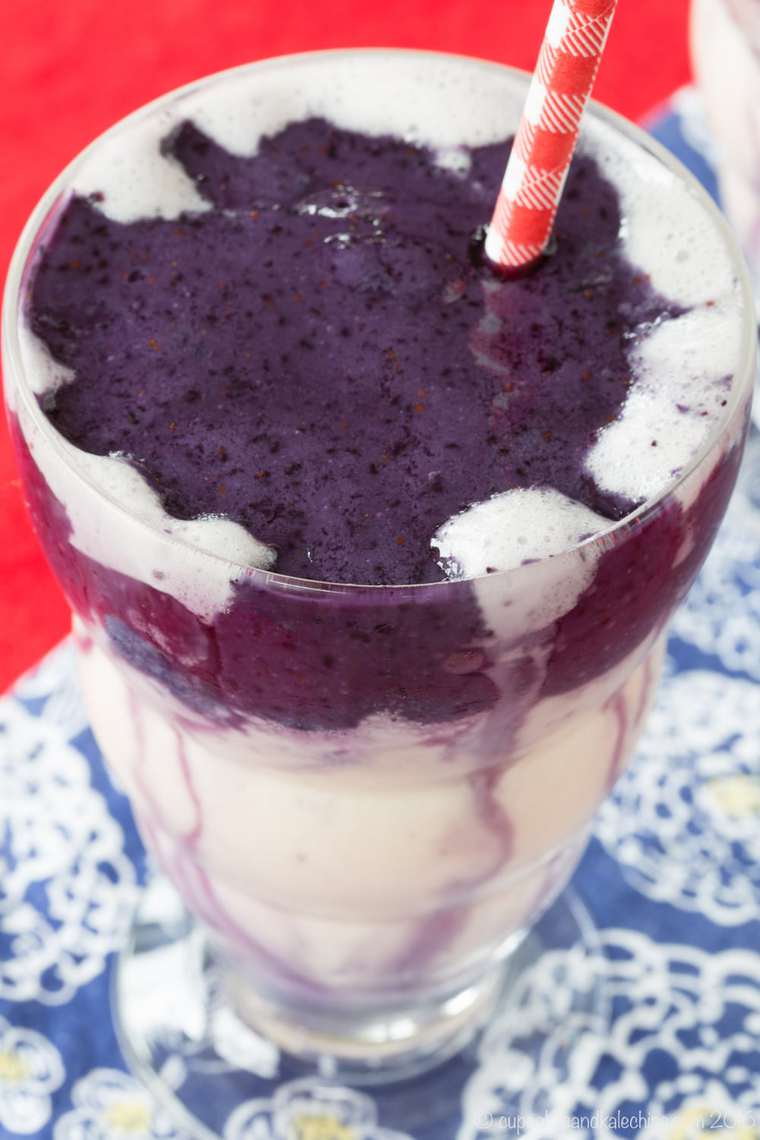 Top view of a blueberry smoothie with a red and white striped straw.