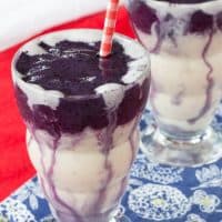 Two Honey and Vanilla Swirled Blueberry Smoothies side by side with red and white striped straws.