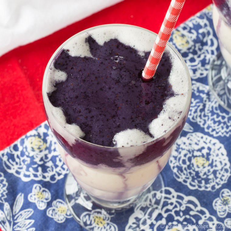 Top view of a blueberry smoothie with a red and white striped straw.