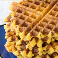 A stack of Cheesy Polenta Waffles on a blue plate.