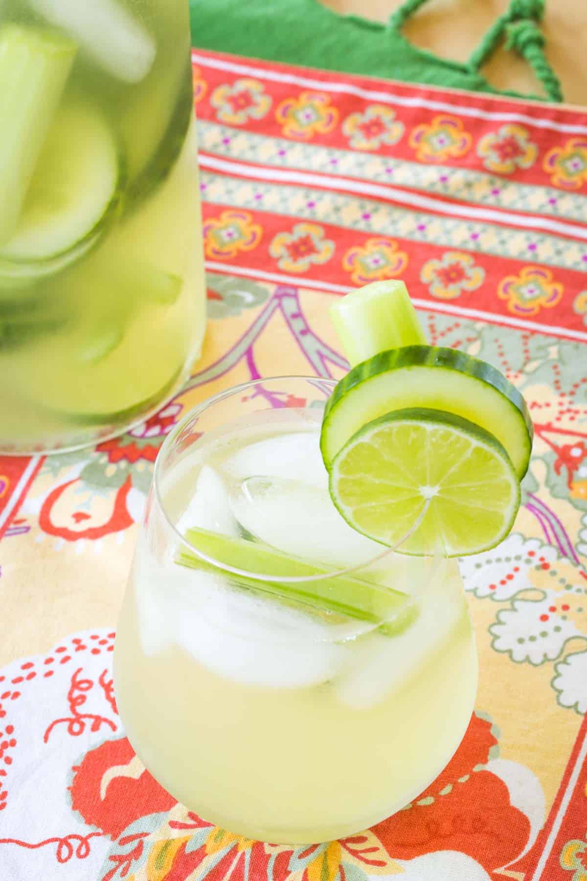 cucumber gimlet white sangria in a glass and a pitcher with celery and cucumber slices floating in both