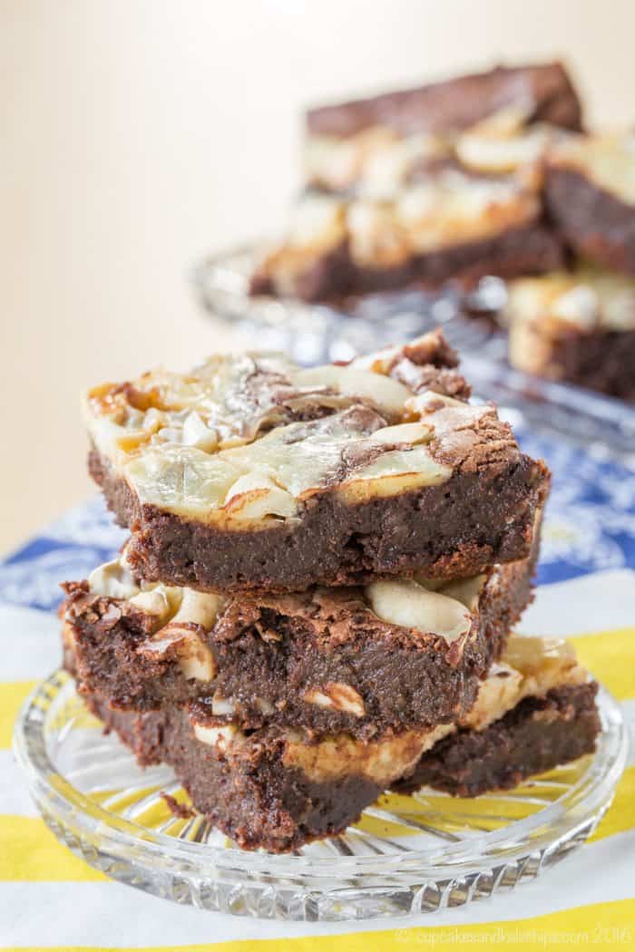 Caramel cashew cheesecake swirl brownies stacked on a plate.