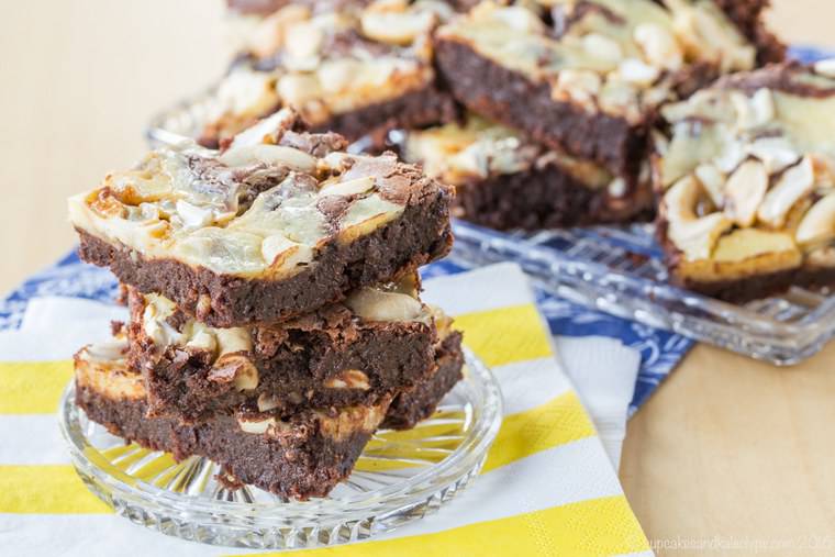 Stack of caramel cashew brownies on a glass plate.