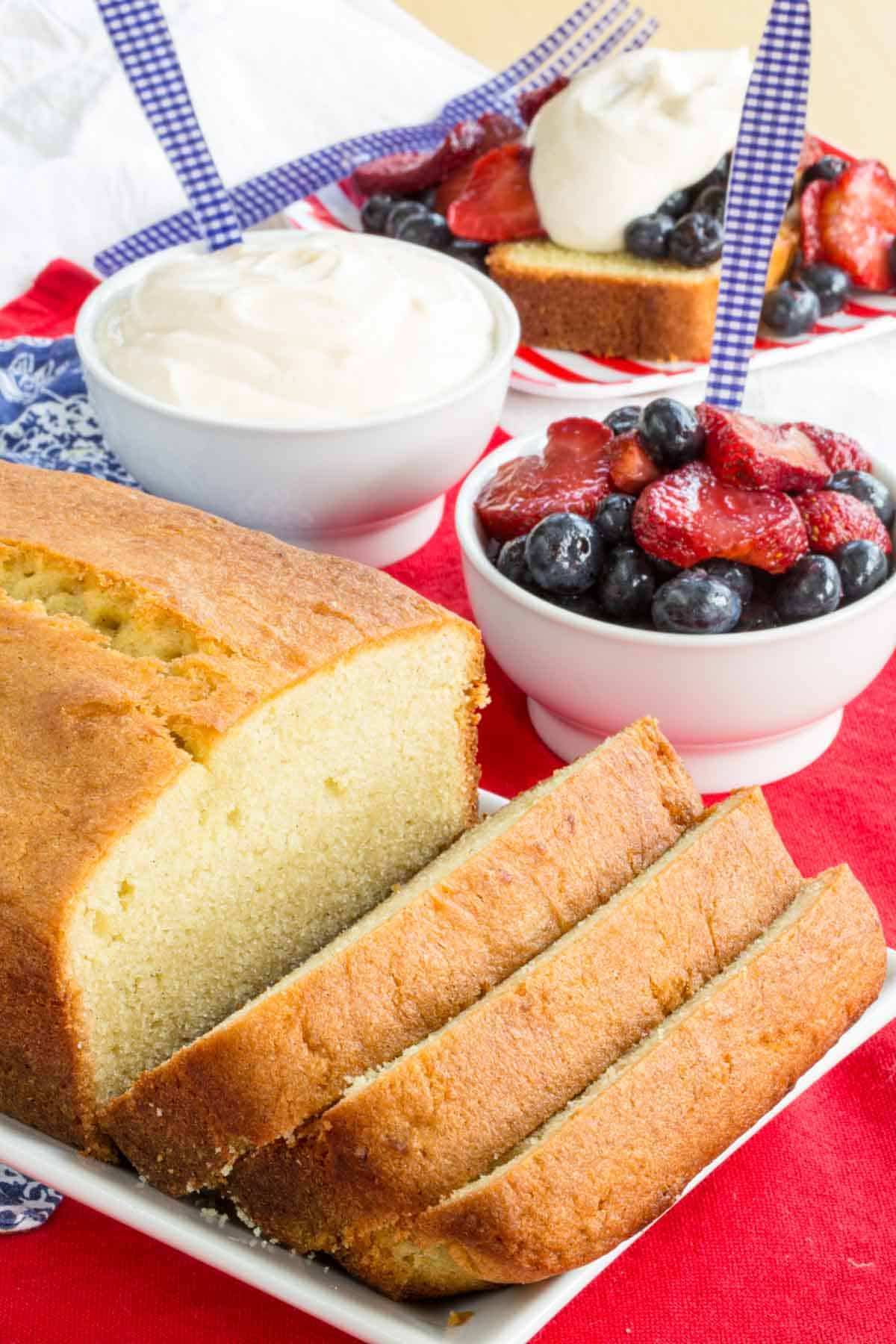 Pound cake next to a bowl of yogurt and a bowl of fruit.