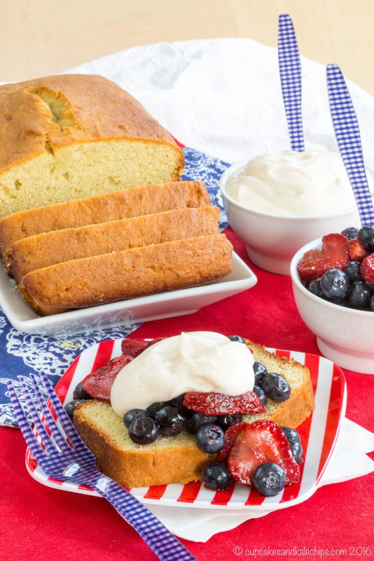 A sliced loaf of pound cake with one slice on a plate topped with mixed berries.