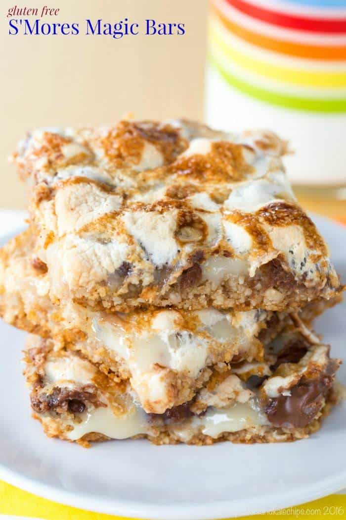 Three s'mores bars stacked on a plate with a glass of milk in the background.