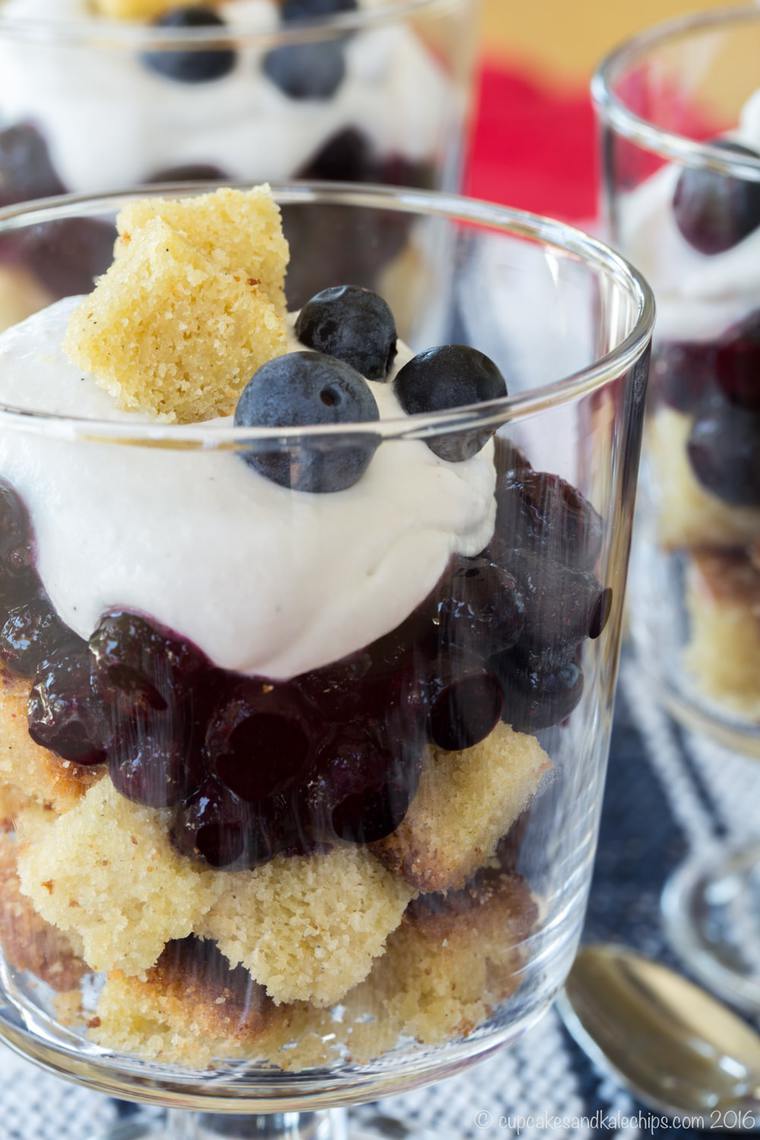 Close up of a mini blueberry and coconut cream trifle in a small glass.