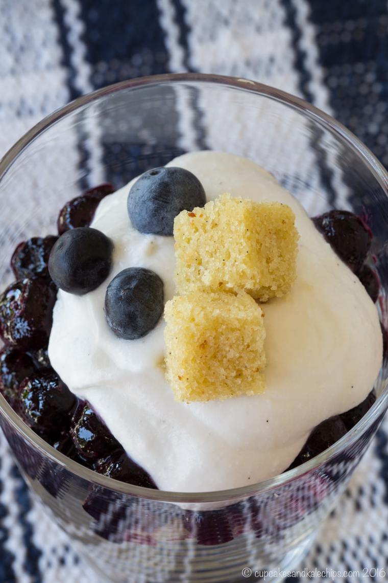 Close up top view of a mini blueberry and coconut cream trifle in a glass.