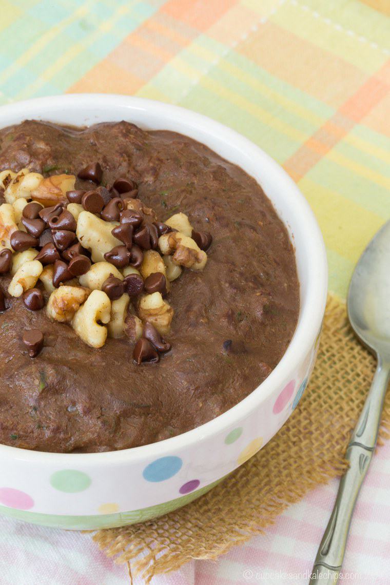 A bowl of zucchini oatmeal stopped with crushed nuts and chocolate chips.